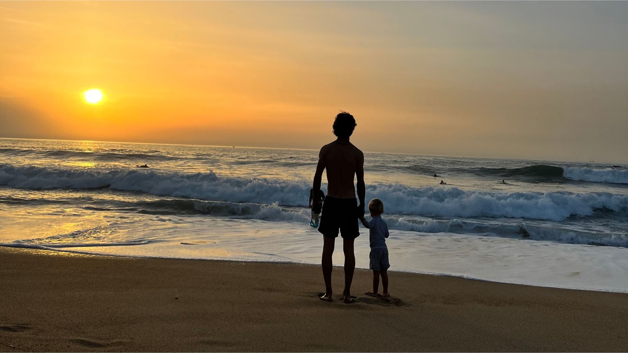 Enfant et papa face au coucher de soleil à l'océan