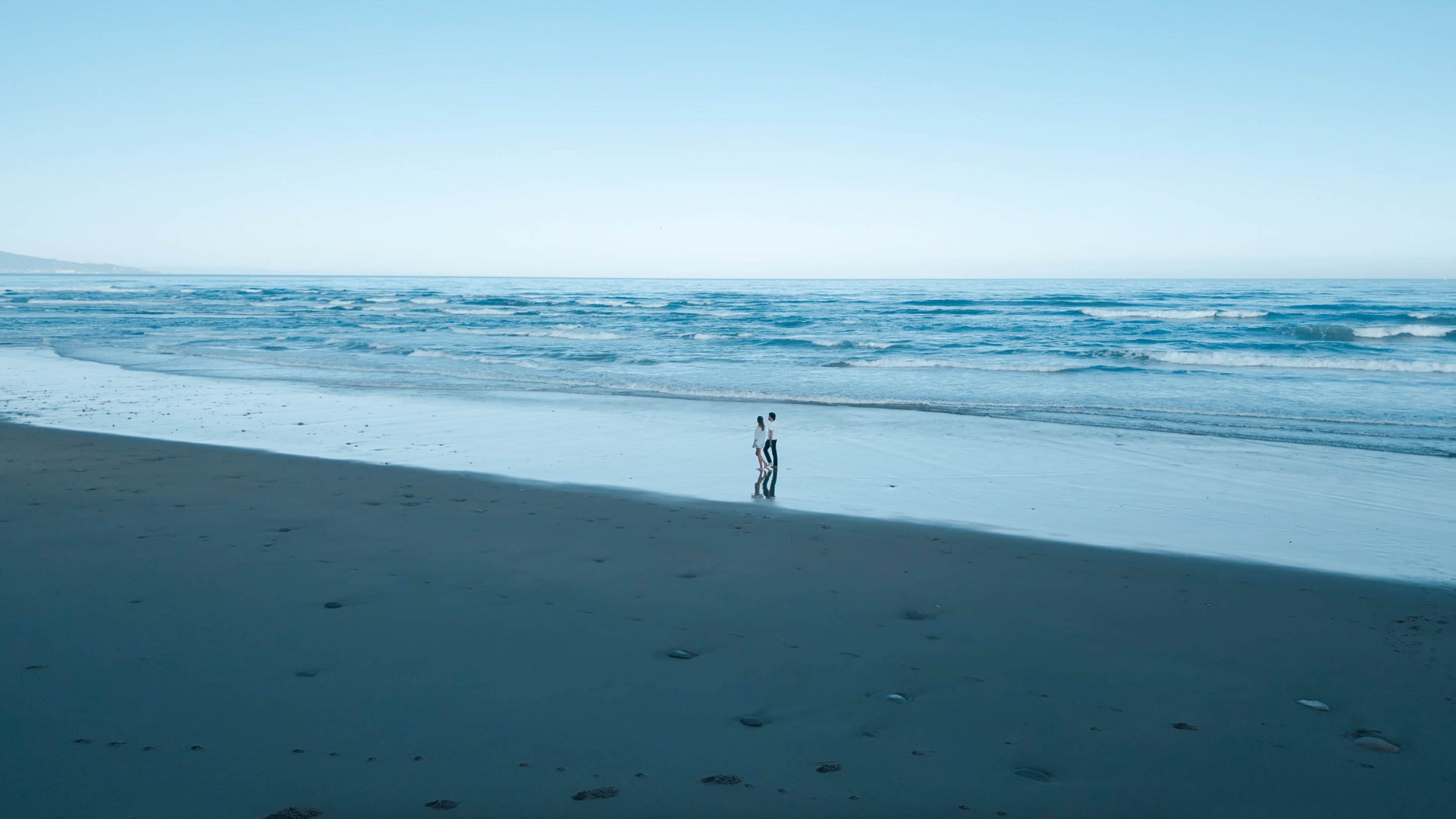 homme et femme marchant le long de la plage vue aérienne